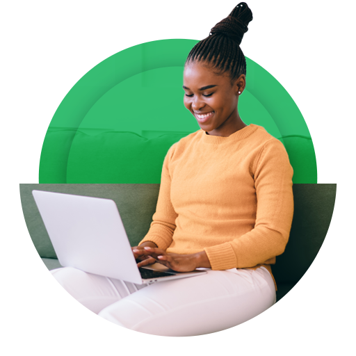 Jovem negro, sorrindo, em pé na rua olhando o celular.